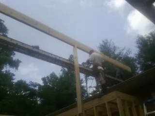 Carpenter setting a ridge beam over a new addition frame — Ice Dam Removal by Roofing Brothers in Standish