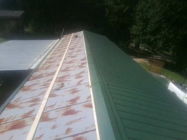 Old rusted panels beside newly installed green metal roofing — Wind Damage Roof Repair by Roofing Brothers in Standish
