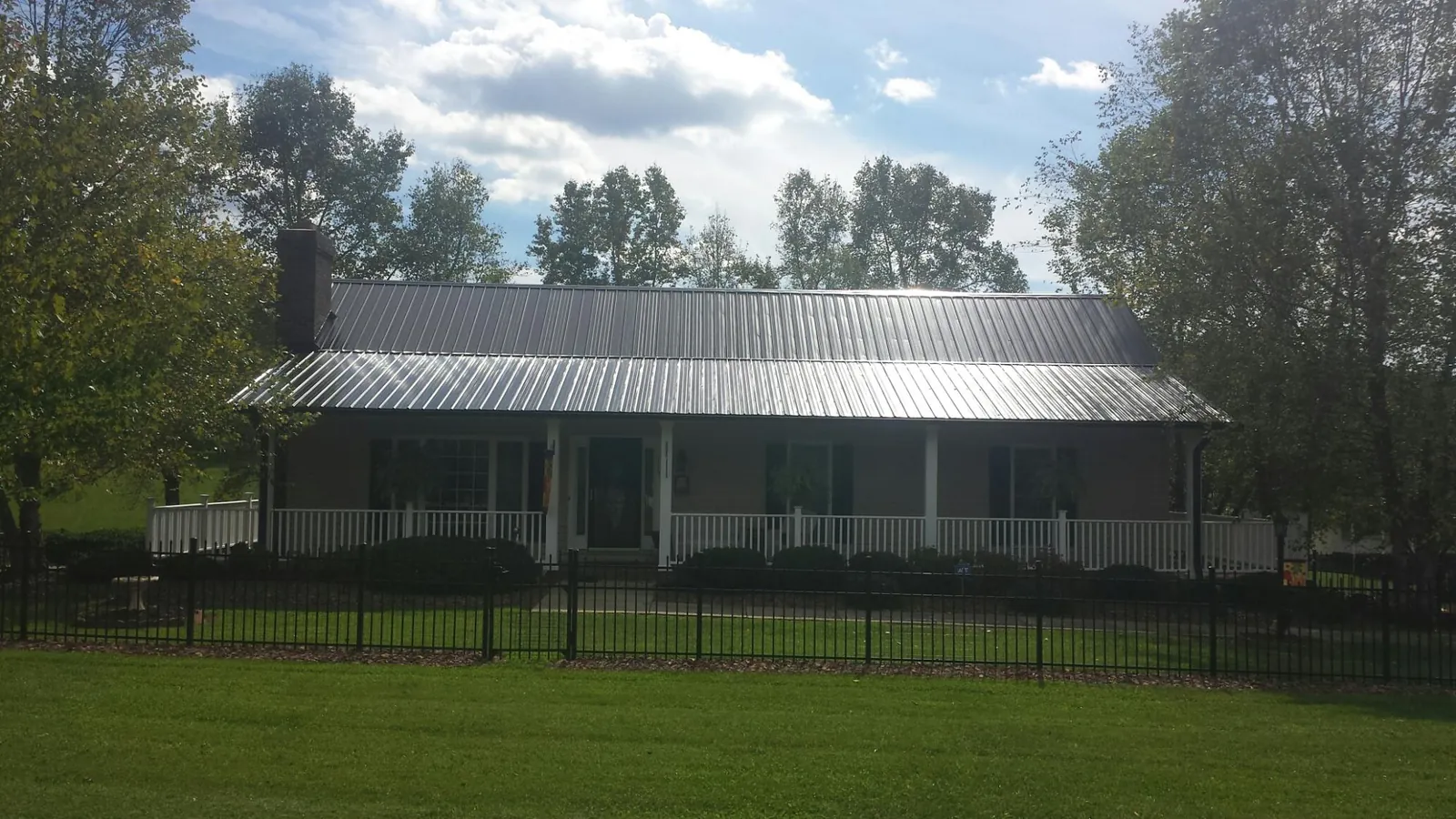 Gray metal roof on a brick ranch with a full width front porch — Gutter Guard Installation work by our crew in Standish