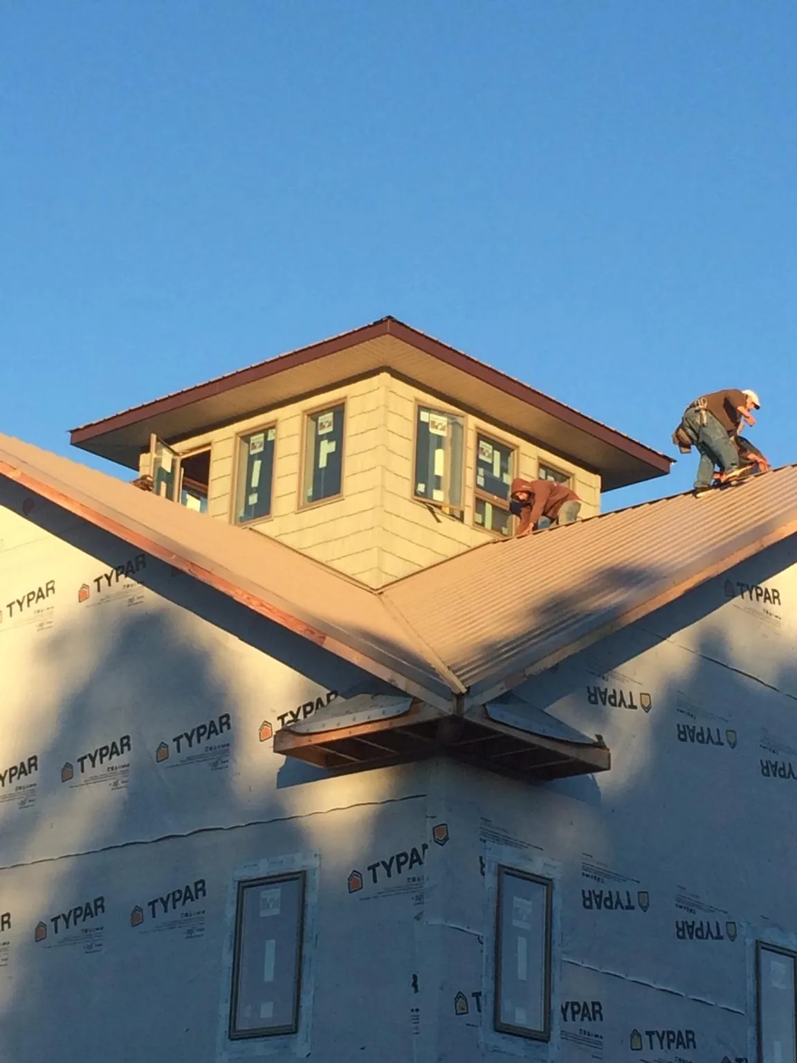 Roofers working around a rooftop cupola on a new metal roof at sunset — Roof Waterproofing in Standish by Roofing Brothers